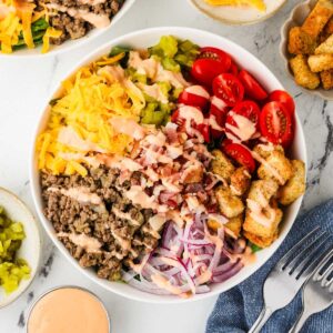 Burger bowl salad with seasoned ground beef, cheese, and fresh burger toppings.