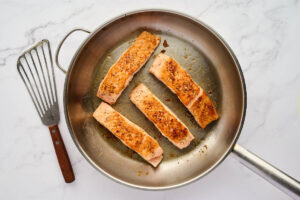 Searing salmon fillets in a skillet.