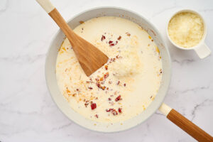 Adding cream and parmesan cheese to the sauce.