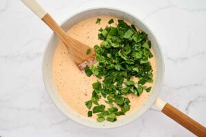 Adding chopped spinach to the cream sauce.