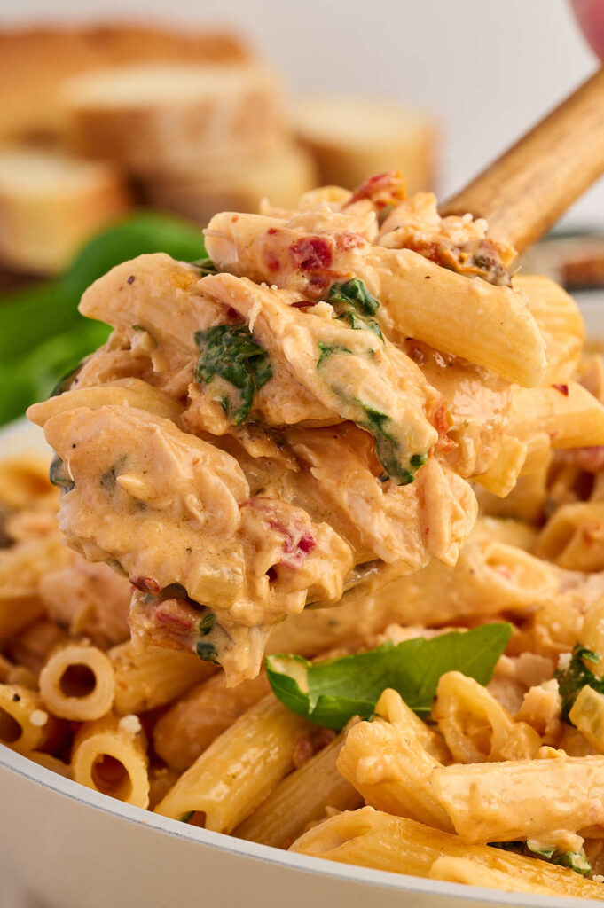 A spoon scooping out a serving of creamy salmon pasta.