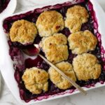 Easy blueberry cobbler in a square baking dish with bubbling blueberry filling.