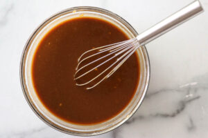 Whisking a miso marinade glaze in a glass bowl.