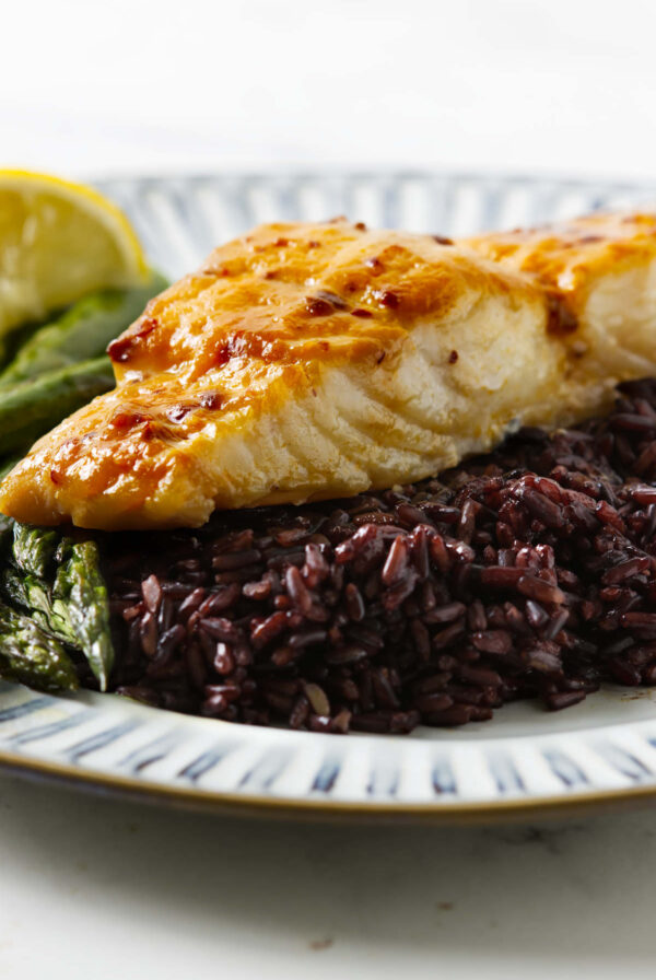 A fillet of miso glazed halibut on a bed of black rice.