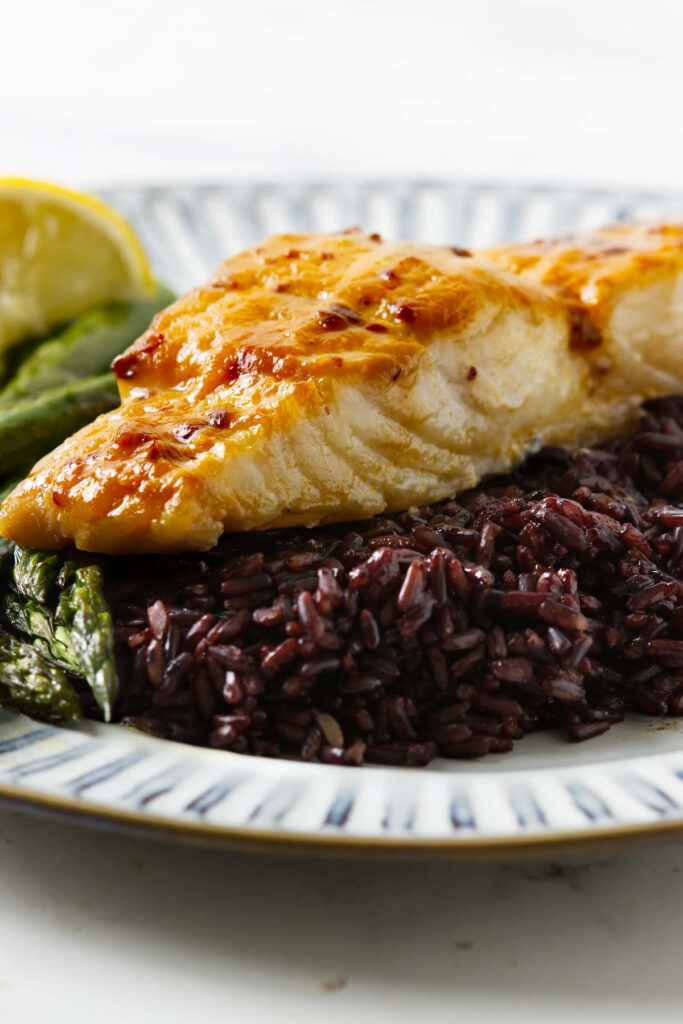 A fillet of miso glazed halibut on a bed of black rice.