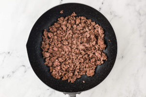 Browned ground beef cooking in a skillet for a quick stir fry dinner.