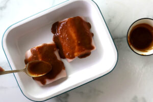 Spreading miso glaze over two fillets of fish.