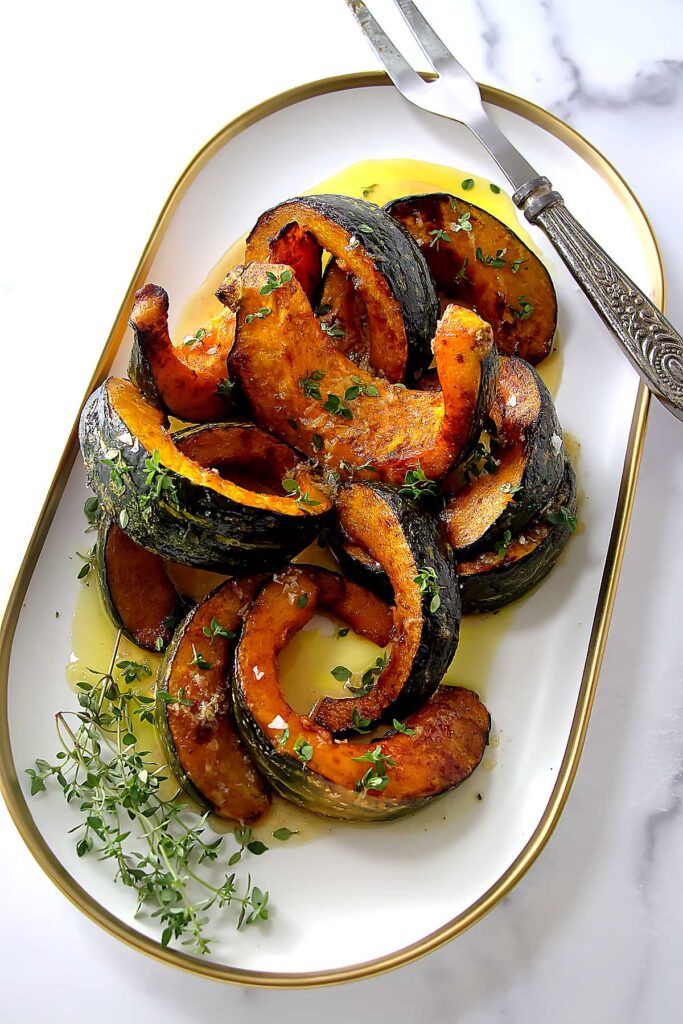 A platter filled with hot honey squash slices next to a serving fork.