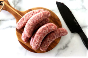 Cutting slits in raw sausage links.