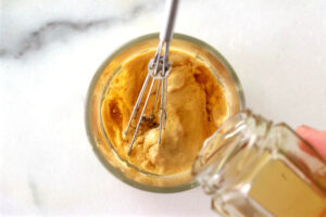 Combining oil with honey and mustard in a jar.