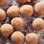 Chocolate truffles coated in cocoa powder on a white surface.