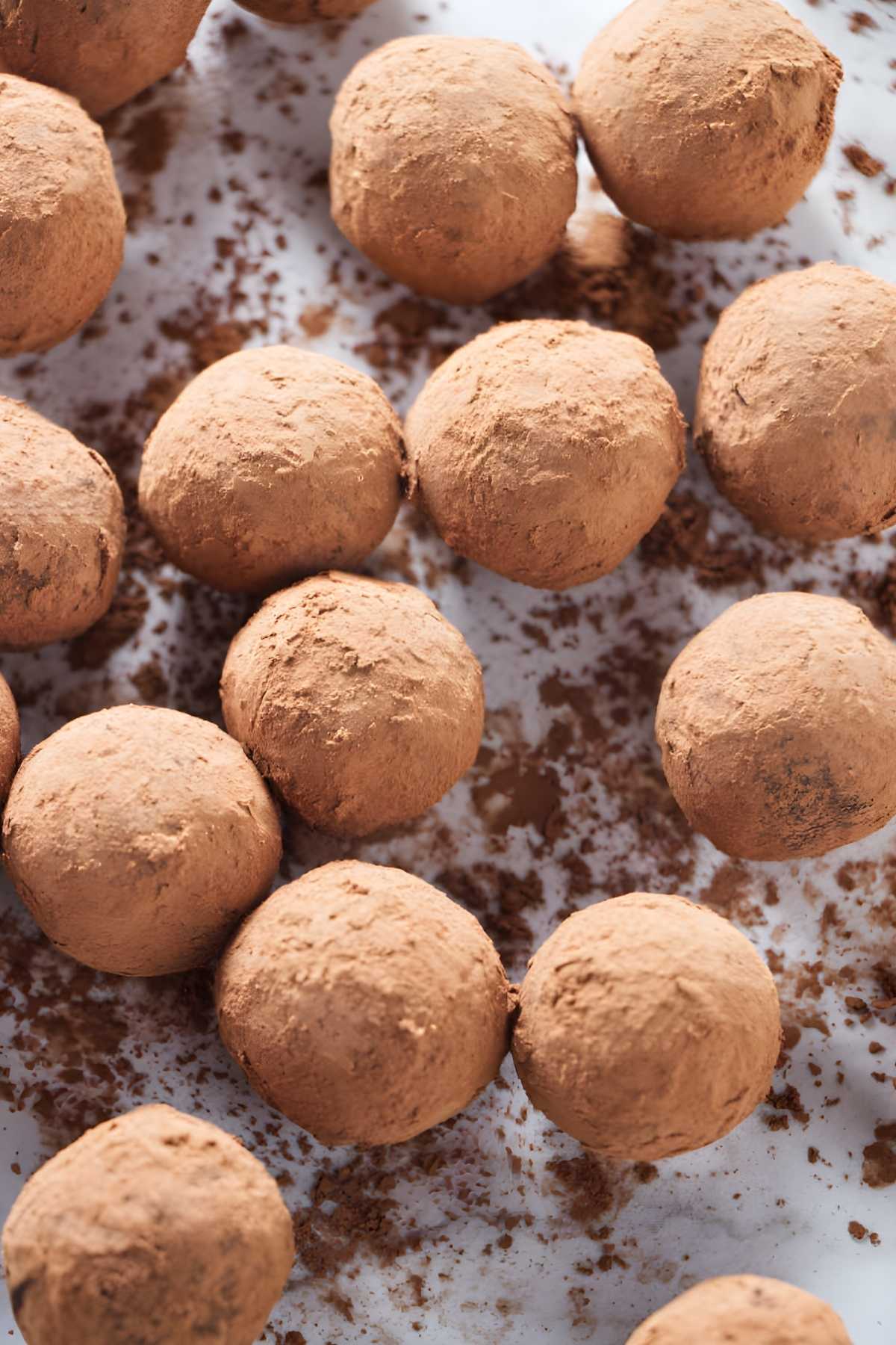 Chocolate truffles coated in cocoa powder on a white surface.