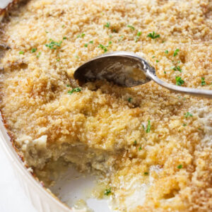 A spoon scooping potatoes au gratin from a dish.