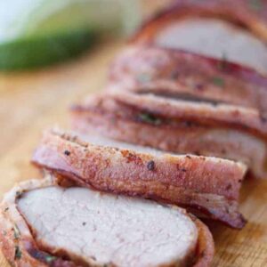A smoked pork tenderloin wrapped in bacon and sliced.