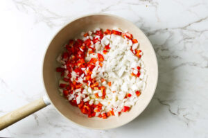 Diced onions and bell peppers in a skillet.