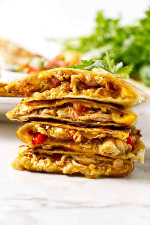 Cheesy chicken quesadillas stacked, filled with chicken, cheese, red peppers.