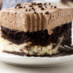 Chocolate and cream cake slice on white plate with fork.