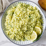 Easy Greek lemon rice recipe served with fresh dill and lemon wedges.