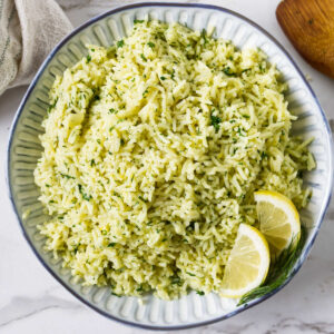 Easy Greek lemon rice recipe served with fresh dill and lemon wedges.
