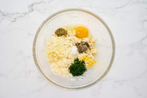 Greek chicken meatball ingredients in a mixing bowl.