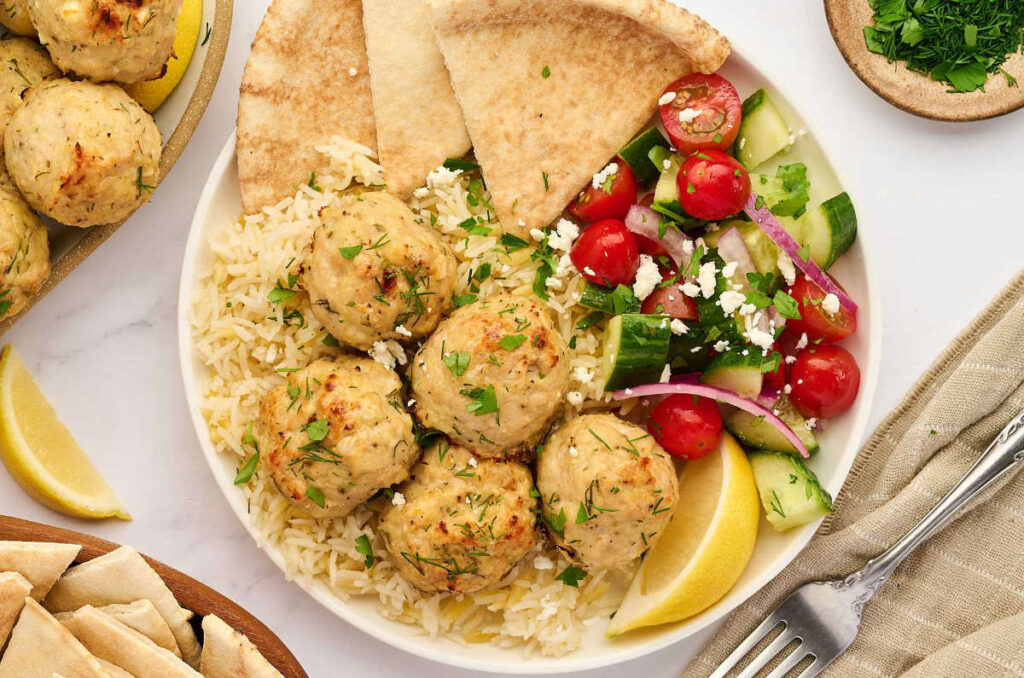 Baked Greek chicken meatballs served with tzatziki and fresh sides.