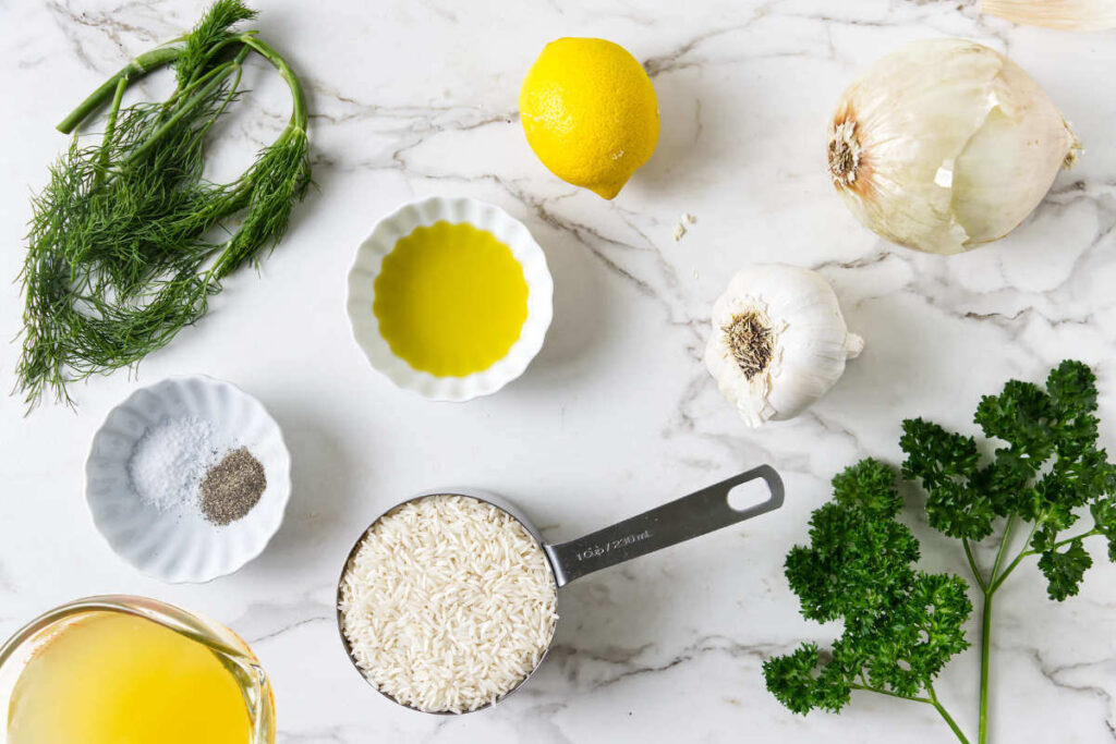 Lemon rice ingredients with long-grain rice, lemon, dill, parsley, onion, garlic, and broth.