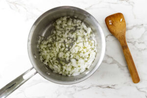 Diced onion softening in a saucepan for lemon rice pilaf.