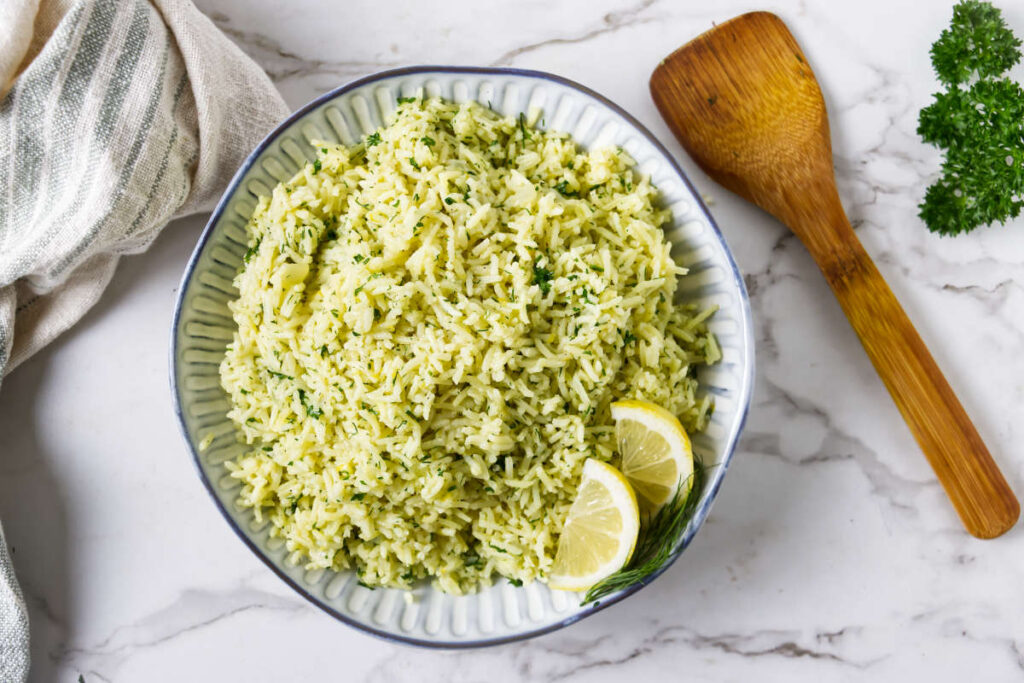 Fluffy lemon rice served in a shallow bowl with dill and lemon.