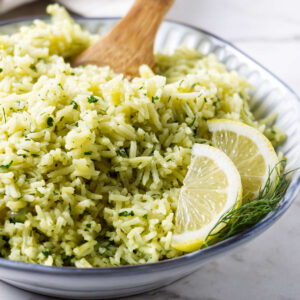 Close-up of lemon dill rice with fresh herbs and lemon slices.