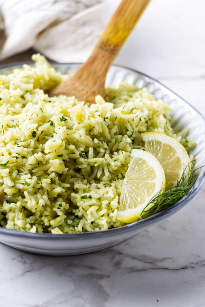 Close-up of lemon dill rice with fresh herbs and lemon slices.