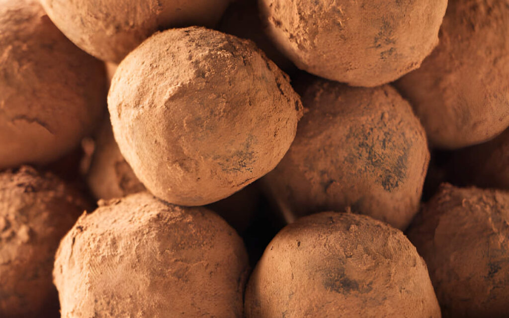 Close-up of chocolate truffles dusted with cocoa powder, stacked together.