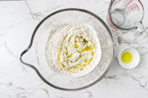 Olive oil and warm water added to flour for pita bread dough.