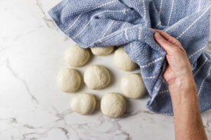 Covered dough balls resting before rolling homemade pita bread.