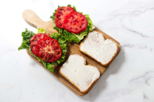 Assembling BLT sandwiches with lettuce, sliced tomatoes, and crisp bacon.