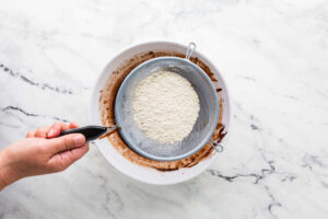 Sifting flour and dry ingredients into the cake batter.