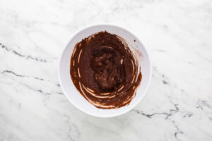 Mixing cocoa powder with hot coffee in a mixing bowl.