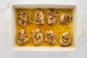Greek lemon chicken ingredients with chicken thighs, lemon, garlic, and herbs.