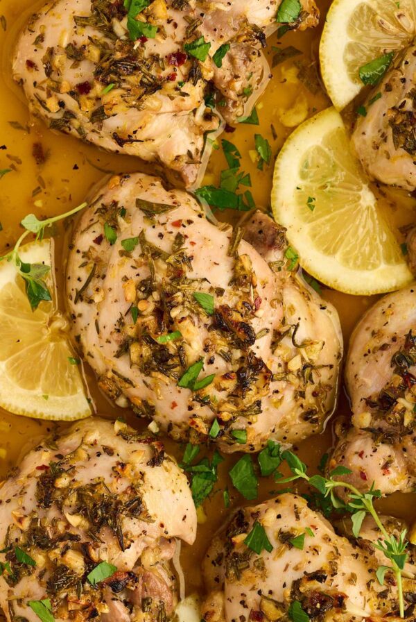 Boneless chicken thighs marinating with lemon, garlic, rosemary, thyme, and oregano.