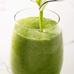 Green smoothie poured into clear glass.