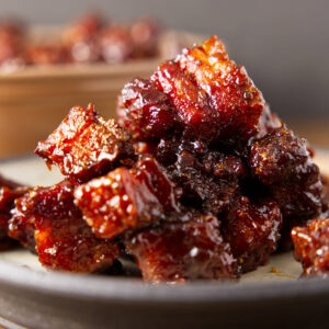 A pile of pork belly burnt ends on a dinner plate.