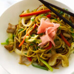 Stir-fried noodles with vegetables and meat, topped with pickled ginger.