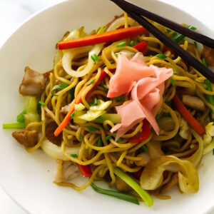 Stir-fried noodles with vegetables and meat, topped with pickled ginger.