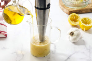 Pouring olive oil into a jar with a stick blender.