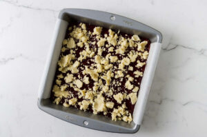 Raspberry crumble bars served on a white plate with jam showing between the layers.