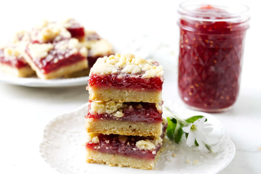 Sliced raspberry shortbread bars with lemon-scented crumbs on top.