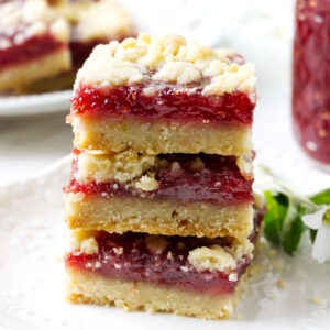 Finished raspberry crumble bars with buttery shortbread crust and raspberry jam filling.
