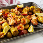Finished sheet pan shrimp boil served hot with lemon wedges and fresh parsley.