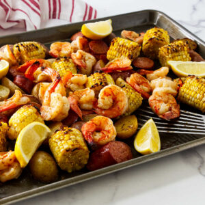 Finished sheet pan shrimp boil served hot with lemon wedges and fresh parsley.