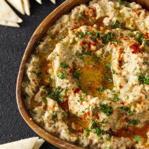 Smoky baba ghanoush in a serving bowl topped with chopped parsley.