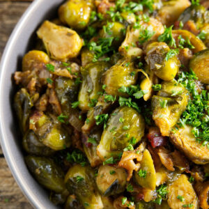 Brussels sprouts in a ceramic serving dish topped with parsley.
